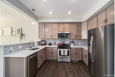 Kitchen with stainless steel appliances, tasteful backsplash, hanging light fixtures, dark wood-type flooring, and recessed lighting