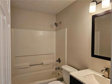Bathroom with toilet, vanity, shower / bathtub combination, and a textured ceiling