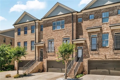 Multi unit property featuring a garage, concrete driveway, brick siding, and stairway