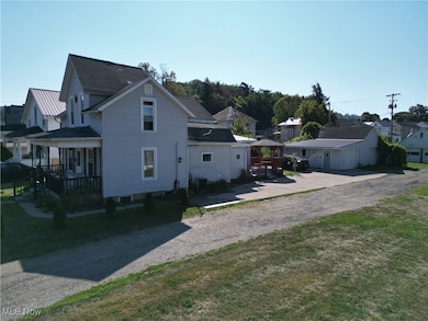 View of side of home with driveway, covered porch, a residential view, and roof with shingles