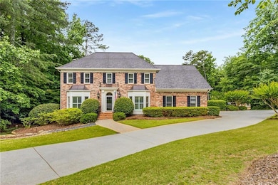 Stately 4-sided brick home on a corner lot with a large circular driveway in addition to more parking outside of the garage.