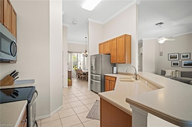 Kitchen with a sink, appliances with stainless steel finishes, ornamental molding, light tile patterned flooring, and baseboards