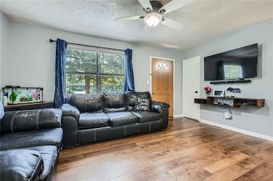 Living area featuring wood finished floors, ceiling fan, and a textured ceiling