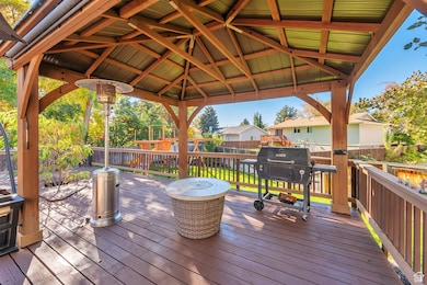 Wooden deck featuring grilling area, a gazebo, a residential view, a fenced backyard, and a playground