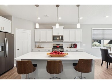 One-level living with dream kitchen featuring an oversized island, quartz countertops, tile backsplash, slate finish appliance package including refrigerator and walk-in pantry. Photo of model home, colors and finishes will vary.