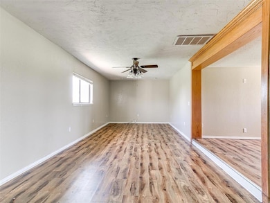 Unfurnished room featuring a ceiling fan, wood finished floors, and a textured ceiling