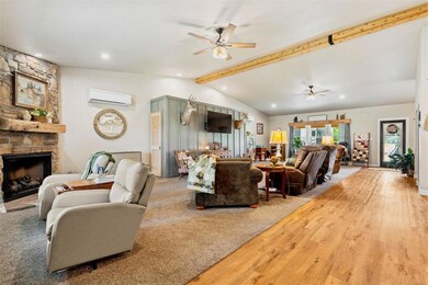 Living area with ceiling fan, a wall mounted air conditioner, wood finished floors, a fireplace, and recessed lighting