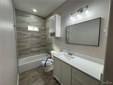 Bathroom with toilet, vanity, wood finished floors, shower / bath combination, and recessed lighting