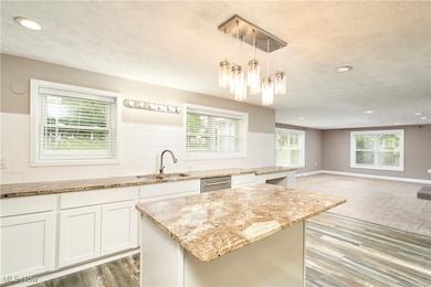 Kitchen featuring a textured ceiling, recessed lighting, hanging light fixtures, white cabinetry, and plenty of natural light