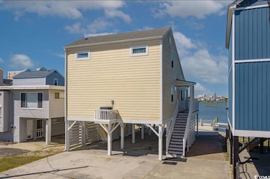 Back of property featuring a carport, driveway, stairway, and a water view