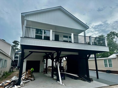 Raised beach house featuring a balcony and a carport