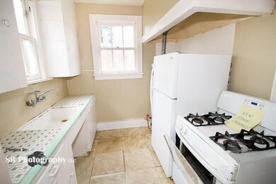 Kitchen featuring white cabinets, sink, stove, and