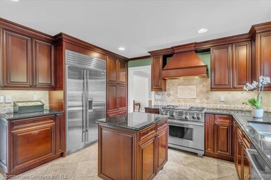 Kitchen featuring dark stone counters, premium appliances, custom exhaust hood, decorative backsplash, and recessed lighting
