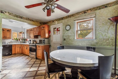 Kitchen with light countertops, wallpapered walls, hanging light fixtures, brown cabinets, and stainless steel appliances