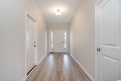 Doorway to outside with light wood-type flooring and baseboards