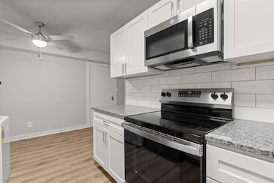 Kitchen featuring ceiling fan, white cabinetry, ta