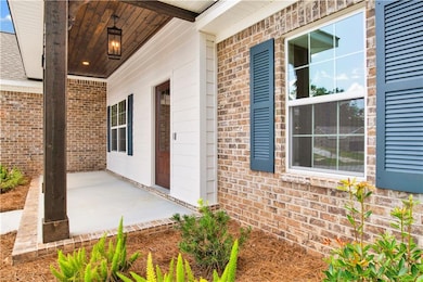 Doorway to property featuring brick siding and a patio area