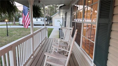 Wooden terrace with an outdoor structure, driveway, a porch, a garage, and a lawn
