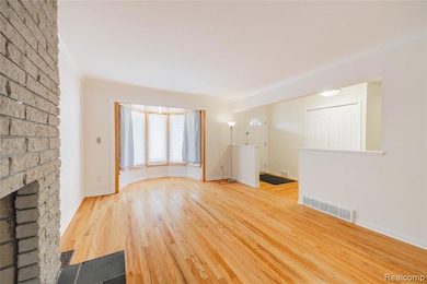 Unfurnished living room featuring wood finished floors, ornamental molding, and a fireplace