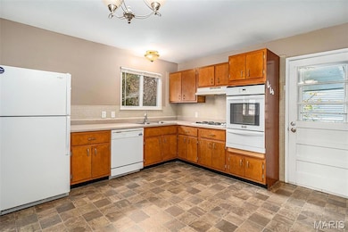 Kitchen with white appliances, light countertops, tasteful backsplash, brown cabinetry, and a warming drawer