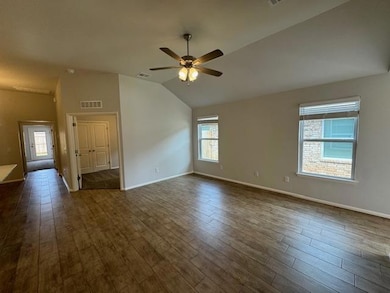 Empty room featuring lofted ceiling, plenty of natural light, dark wood-style flooring, and ceiling fan