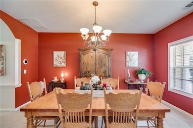 Dining space featuring light carpet and a chandelier