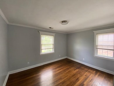 Spare room featuring dark wood-type flooring and ornamental molding
