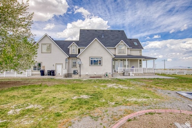 Back of property featuring a shingled roof, stucco siding, covered porch, and fence