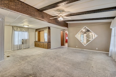 Carpeted empty room featuring beamed ceiling and ceiling fan