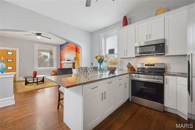Kitchen featuring a ceiling fan, appliances with stainless steel finishes, a peninsula, and a kitchen breakfast bar