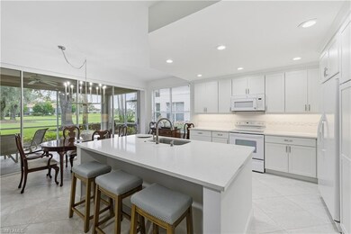 Kitchen with white appliances, a chandelier, a kitchen bar, light tile patterned floors, and recessed lighting