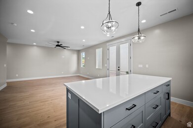 Kitchen featuring french doors, recessed lighting, decorative light fixtures, a kitchen island, and gray cabinets