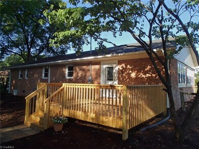 Door from sunroom onto the new deck shaded by dogwood tree.
