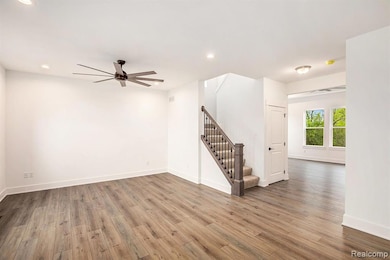 Unfurnished living room featuring stairway, wood finished floors, recessed lighting, and a ceiling fan