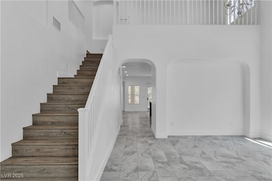 Stairs with arched walkways, a towering ceiling, and marble finish flooring