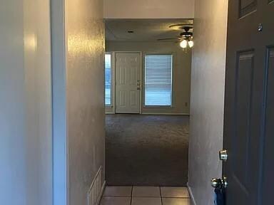 Corridor featuring light colored carpet and light 