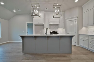 Kitchen featuring backsplash, an island with sink, light hardwood / wood-style flooring, and pendant lighting