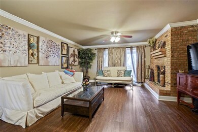 Spacious living room features wood floors, brick w