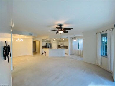 Unfurnished living room featuring ceiling fan, light colored carpet, a chandelier, and arched walkways