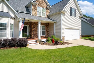 Craftsman house with stone siding, a porch, roof with shingles, driveway, and a front lawn