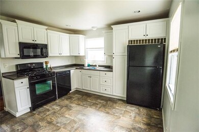 Spacious kitchen with white cabinetry and black ap