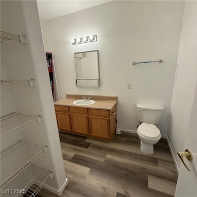 Full bath with vanity, dark wood finished floors, and a spacious closet