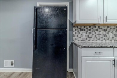 Kitchen featuring white cabinetry, black fridge, l