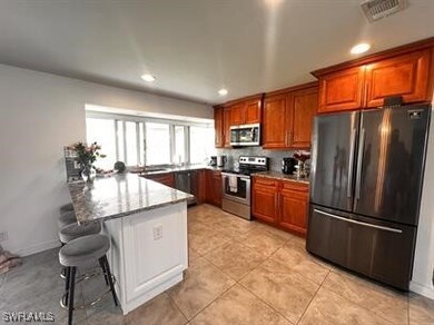 Kitchen featuring a kitchen breakfast bar, appliances with stainless steel finishes, kitchen peninsula, and light stone counters