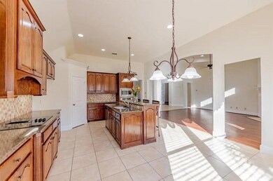 Kitchen with stainless steel microwave, decorative light fixtures, light tile patterned flooring, sink, and a kitchen island with sink
