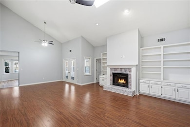 Unfurnished living room featuring high vaulted ceiling, dark wood-style flooring, a brick fireplace, ceiling fan, and recessed lighting