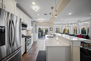 Kitchen with light countertops, dark tile patterned flooring, a sink, a kitchen island with sink, and appliances with stainless steel finishes