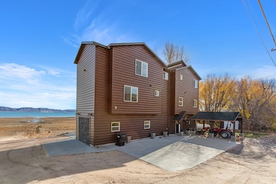 Rear view of house with faux log siding, a water view, and a patio
