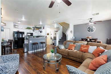 Living area featuring ceiling fan, dark wood finished floors, and stairs