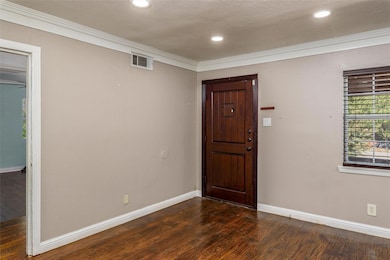 Foyer entrance featuring crown molding, dark hardw